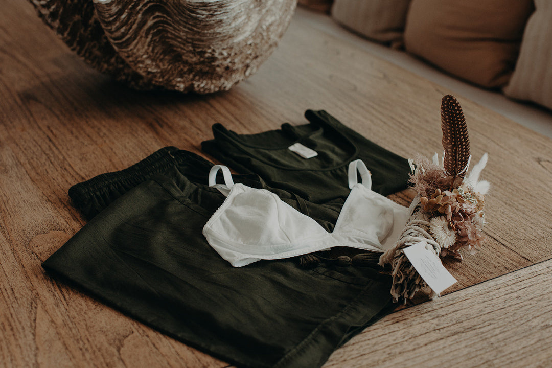 flatlay of clothes folded on floor with bralette and flowers