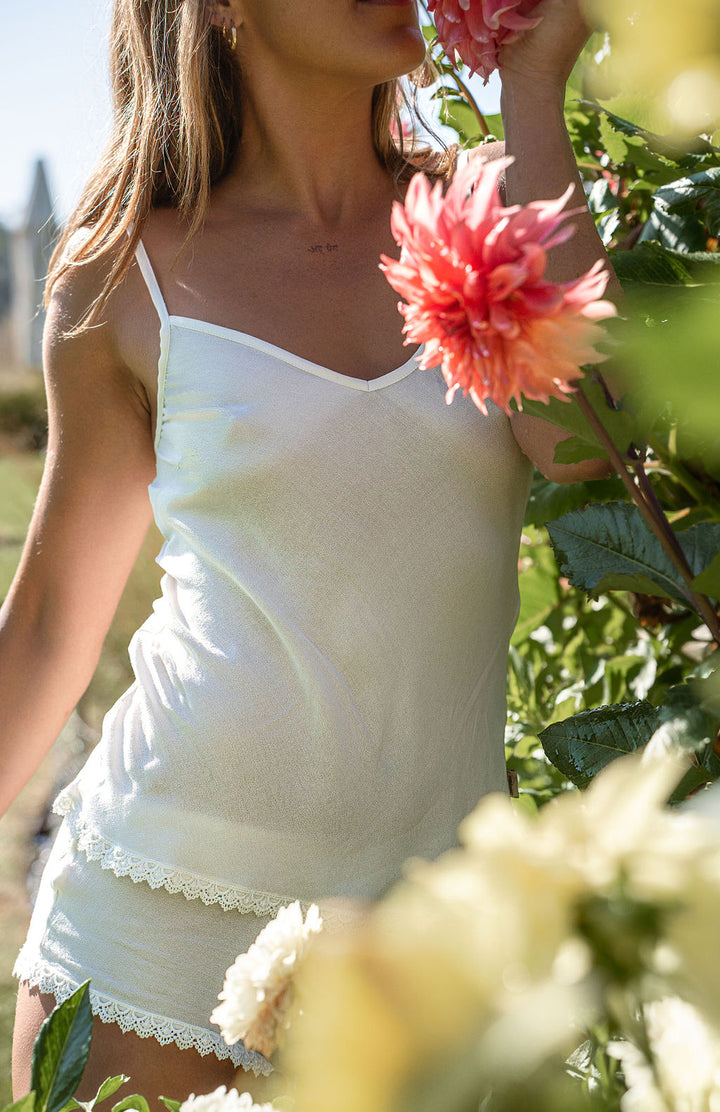 Model smelling flowers in bamboo sleepwear set in natural white