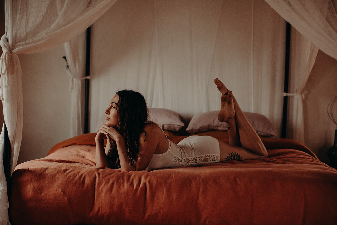 model lying on bed wearing organic cotton romper playsuit