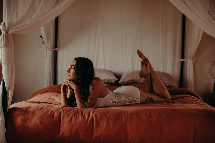 model lying on bed wearing organic cotton romper playsuit