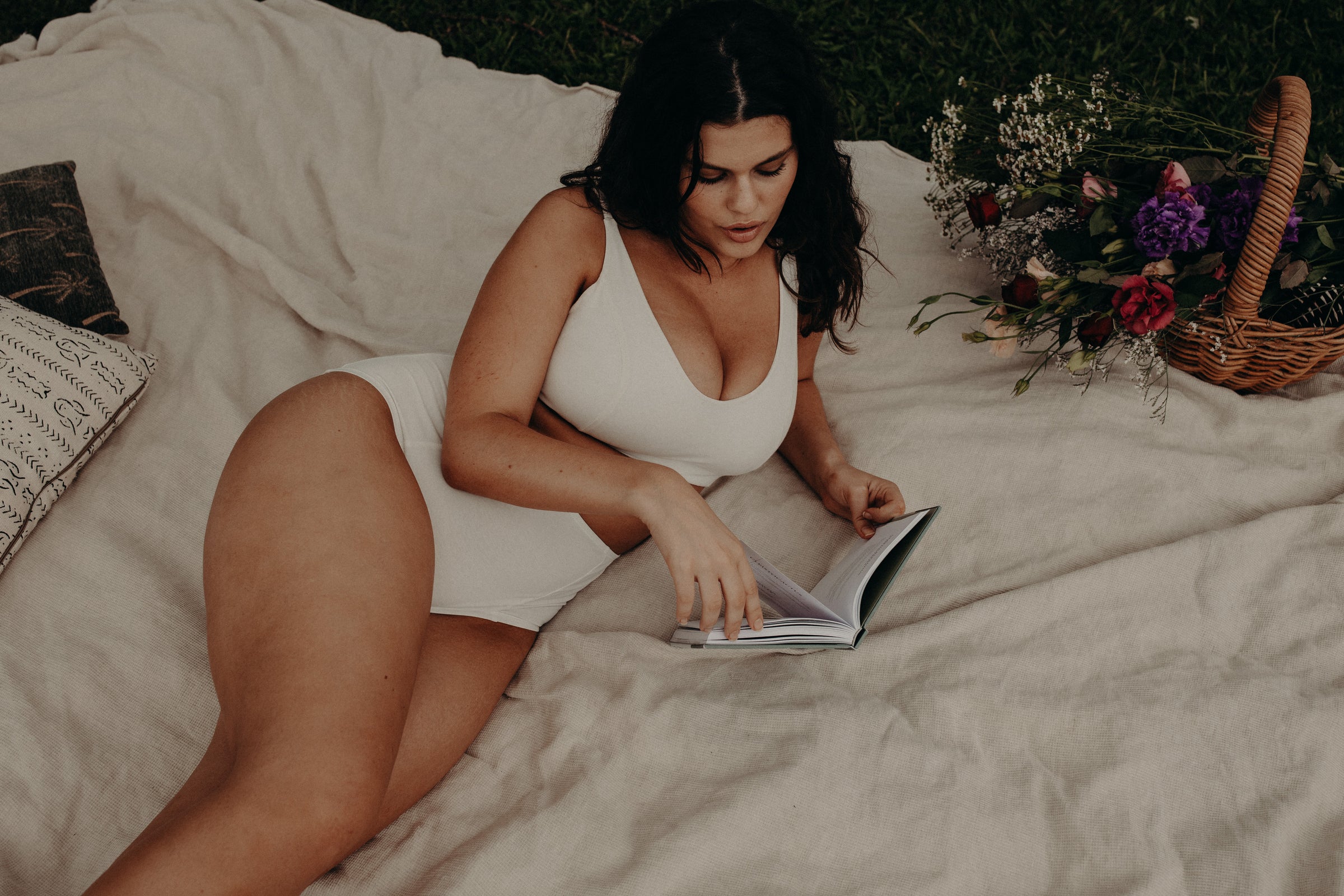Model lying down with book wearing soft cup bra in organic cotton