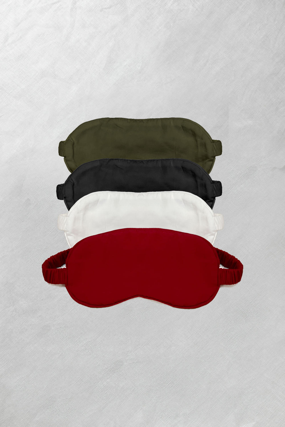 Bamboo sleep masks in olive, black, and red laid out flat on a white background