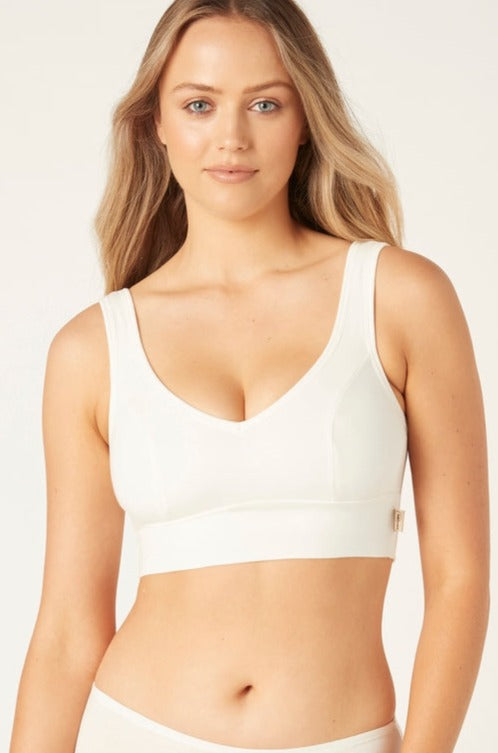 A woman wearing a natural white full cup crop top bra with wide straps.