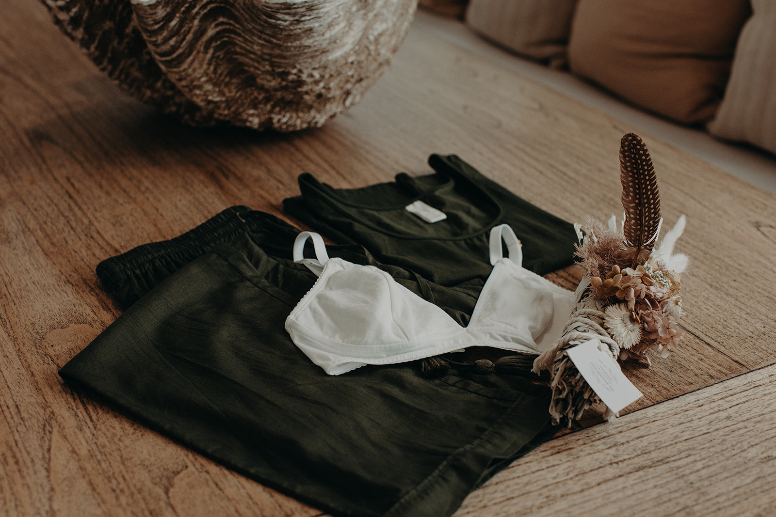 flatlay of clothes folded on floor with bralette and flowers