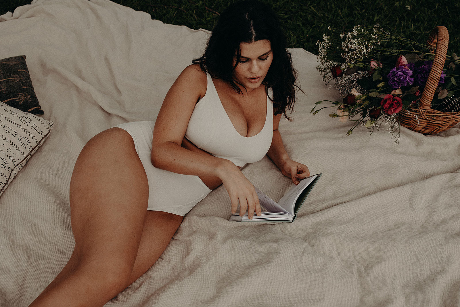 model in cotton underwear lying on picnic blanket with flowers
