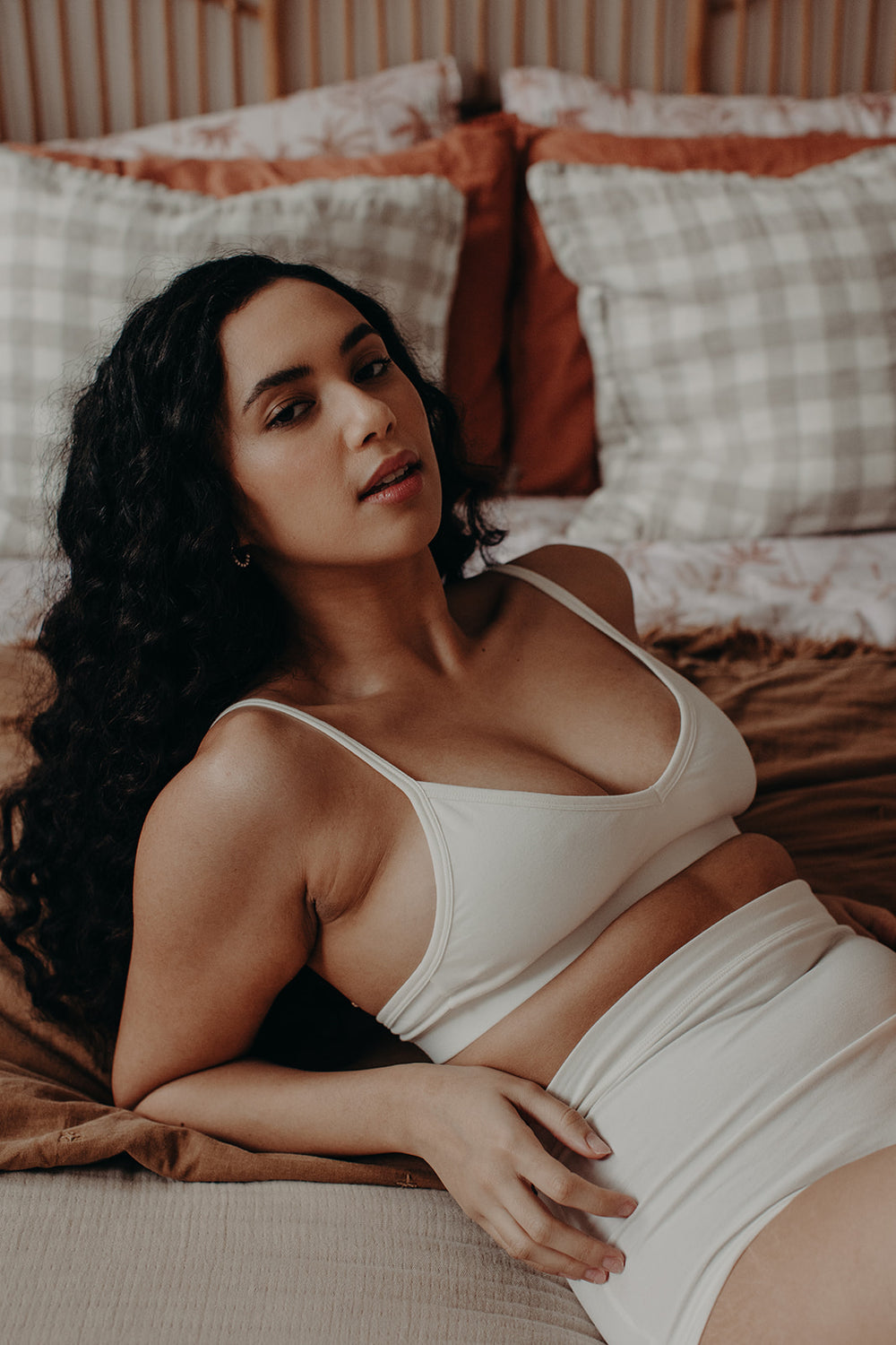 Model lying on bed wearing soft cup bra in organic cotton 