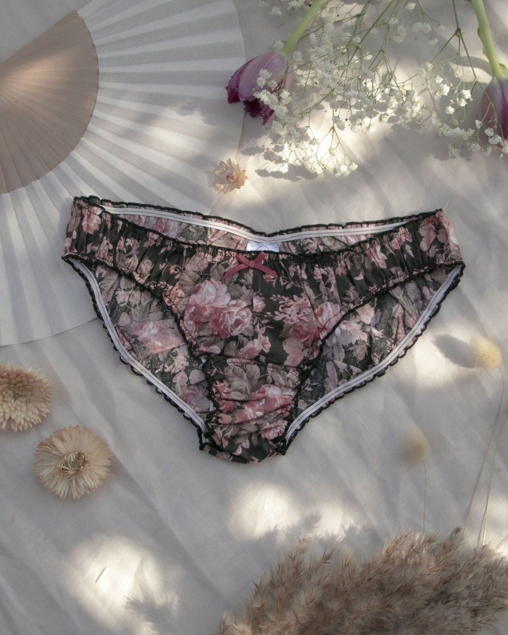 A pair of dark rose floral ruffle knickers laid out flat with a pattern of flowers and a soft elastic band visible, cotton floral underwear, cotton panties