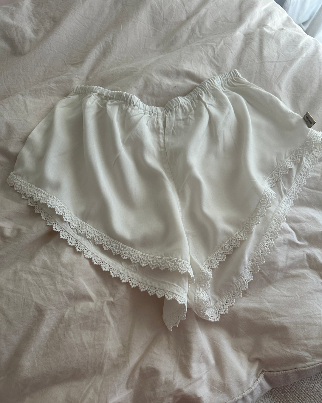 White lace-trimmed underwear on a light-colored fabric background