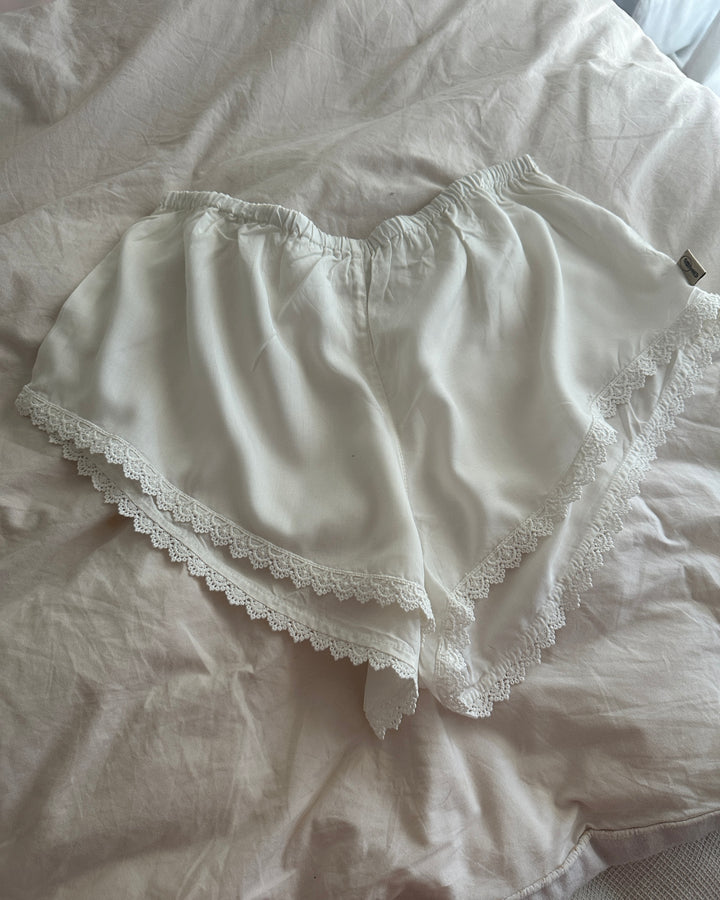 White lace-trimmed underwear on a light-colored fabric background