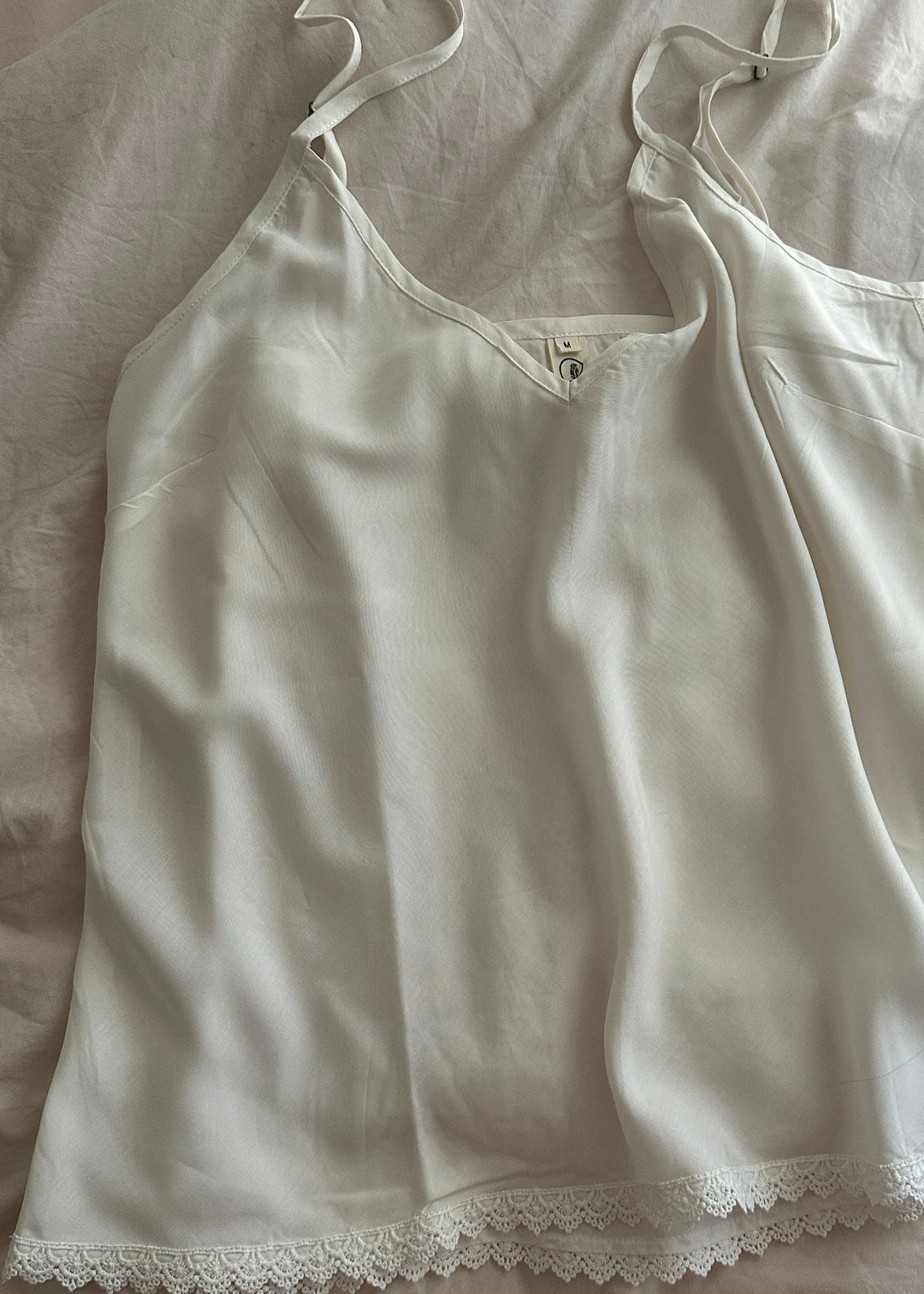 White lace-trimmed top on a light-colored fabric background