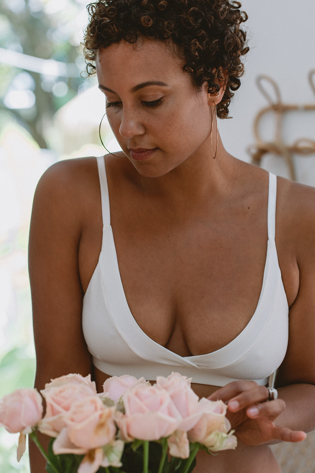 Woman in white bra holding pink roses with a blurred background