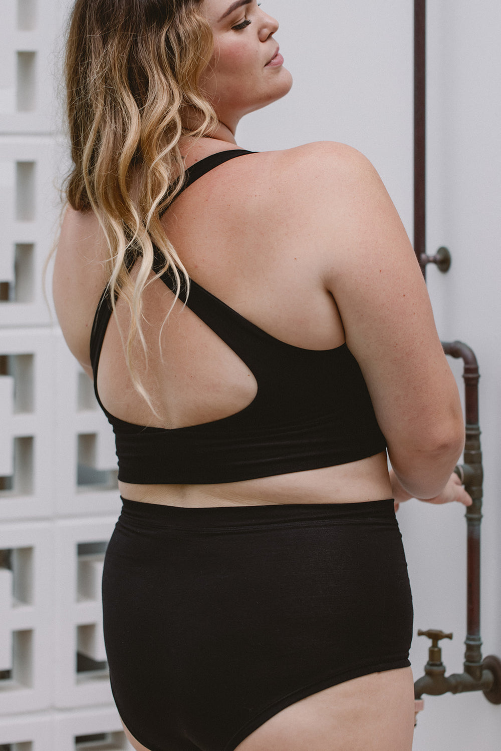 Person wearing a black sports bra and high-waisted underwear set outdoors.