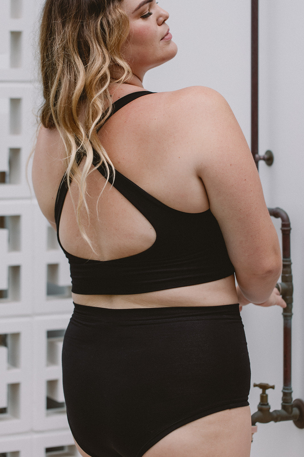 Person wearing a black sports bra and high-waisted underwear set outdoors.