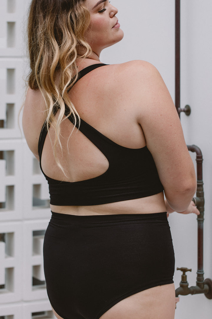 Person wearing a black sports bra and high-waisted underwear set outdoors.
