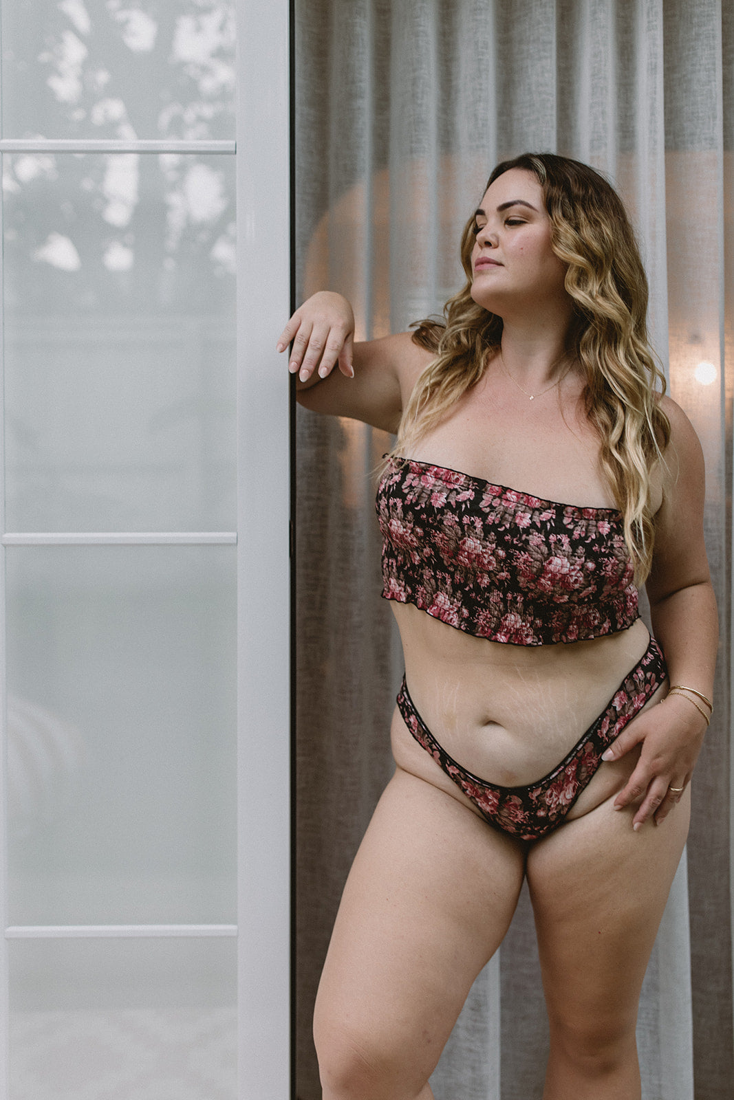 Woman wearing a floral strapless bra standing against a neutral background