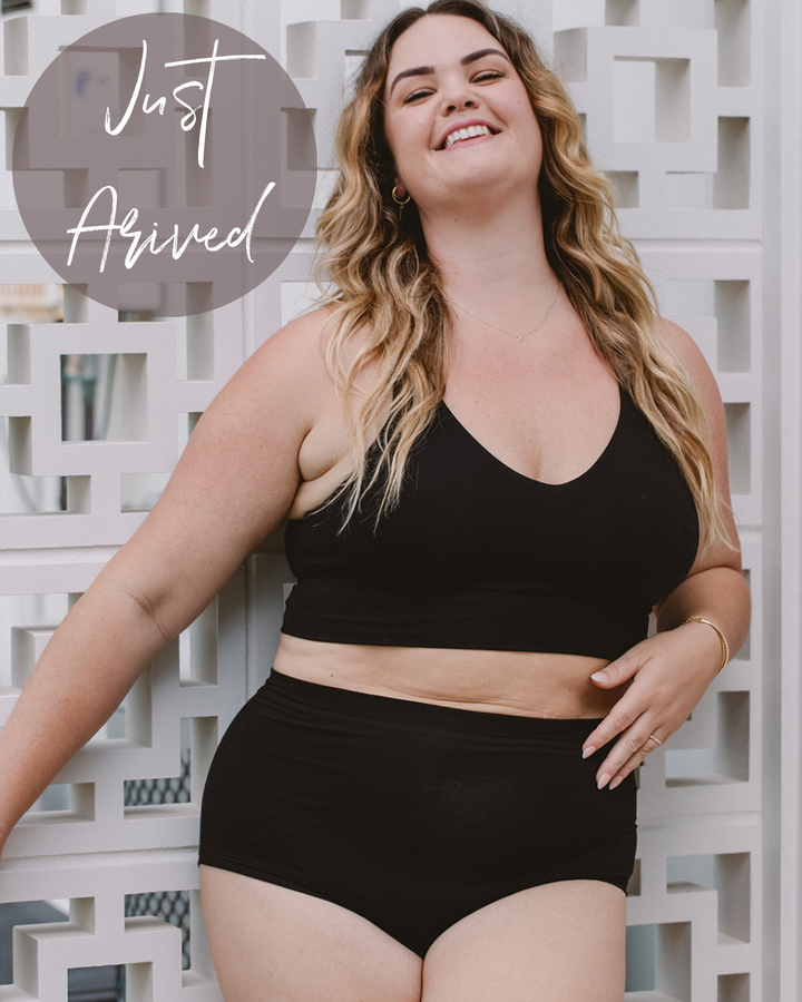 Woman wearing a black bikini set with text 'Just Arrived' in the corner.