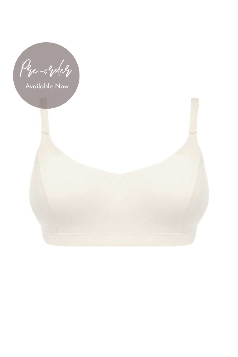 An off-white wireless bralette with thin shoulder straps, shown against a plain white background with a grey circular 'Pre-order Available Now' badge in the top-left corner.