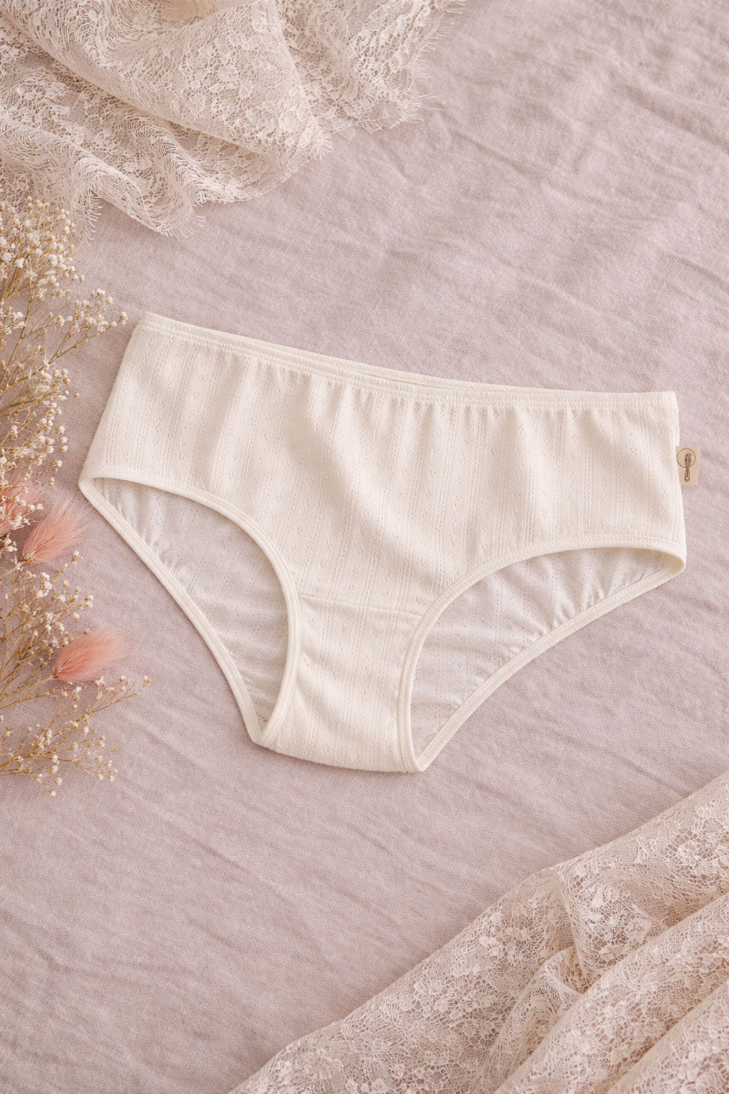 Beige women's underwear on a textured pink surface with floral elements.